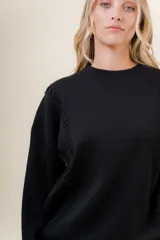 Sweater de tejido fino color beige, con cuello redondo, mangas largas y terminaciones acanaladas. Presenta un diseño con detalles trenzados en diagonal en el frente y corte relajado.