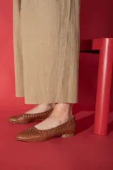 Zapato plano tipo chata, color bronce metalizado, con capellada y forro de cuero vacuno trenzado a mano. Posee un taco bajo de 2,5 cm.