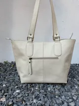 Cartera tote de cuero genuino color azul marino, con doble asa de hombro, costuras verticales y detalle de borla de flecos colgante.