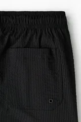 Short de baño negro de sirsaca con cintura elástica y cordón de ajuste. Cuenta con bolsillos laterales y pantaloncillo interior de malla.