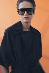Pantalón de tiro medio con diseño wide leg, confeccionado en mezcla de lyocell. Presenta pinzas en el delantero y cierre frontal con cremallera, botón y ganchos metálicos.