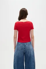 Remera de manga corta color rojo, entallada al cuerpo y con cuello bote, confeccionada en poliéster con textura sutil.
