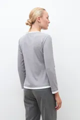 Remera gris melange de tejido canalé con cuello redondo y puños blancos, de manga larga.