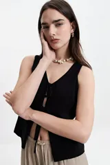 Chaleco tejido negro con escote en V y lazo doble al frente. Diseño liviano, textura suave y fit relajado.