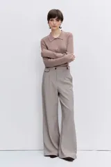 Jersey de punto color beige con cuello polo y cierre frontal de botones. Presenta mangas largas y un ajuste entallado al cuerpo.