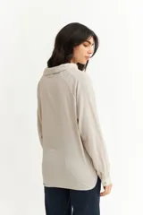 Blusa negra de manga larga con cuello tipo polo y escote en V. Presenta un diseño holgado con textura sutil en la tela y puños abotonados.