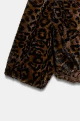 Cazadora de pelo sintético con estampado animal print, diseño con capucha, cierre frontal de cremallera metálica y bajo asimétrico.