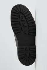 Zapato de vestir tipo derby, color negro, con parte superior lisa, horma redonda, suela con plataforma y piso track.