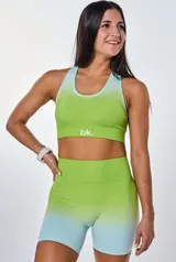 Conjunto deportivo de dos piezas compuesto por un top deportivo de cuello redondo y un short de tiro alto, ambos con diseño degradado en tonos verde lima y celeste. El top presenta el logo de la marca estampado en el frente.