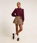 Camisa celeste de crepé con cuello inglés, manga larga abullonada y abotonadura frontal.