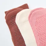 Pack de tres pares de medias de caña media con diseño acanalado y detalle de texto bordado. Incluye un par blanco, uno rosado y uno marrón, todos con suela antideslizante.