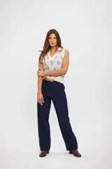 Chaleco de tejido de punto color crema con diseño de rombos en azul claro, escote en V y sin mangas.