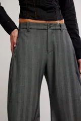 Pantalón de vestir gris con rayas finas, de silueta barrel, tiro medio, con cierre de cremallera y botón, y bolsillos.
