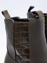 Bota de caña corta color negro, de símil cuero, con plataforma de 7 cm de alto. Cuenta con cierre y pieza de textura croco en laterales.