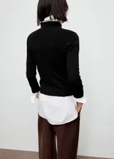 Sweater de punto fino color negro, con cuello perkins, diseño entallado y manga larga.