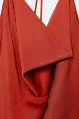 Top sin mangas color terracota, con escote halter ajustable mediante tiras finas y detalle de drapeado fluido en el frente.
