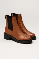 Bota tipo Chelsea de cuero color verde oliva, con paneles laterales elásticos negros y suela track de goma negra con taco cuadrado.