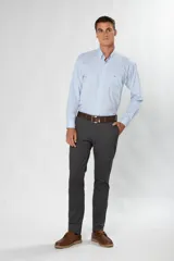 Pantalón de gabardina color marrón claro, corte slim fit, con bolsillos laterales y traseros. Se ajusta a la cintura con cinturón de cuero marrón.