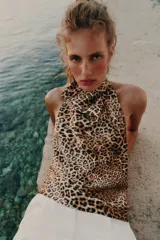 Top halter satinado con estampado de leopardo, cuello desbocado y espalda descubierta con cierre de botón en la nuca.