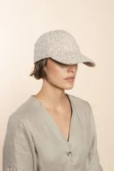 Gorra con visera confeccionada en lana fina sin teñir, con un sutil patrón de tejido en espiga.
