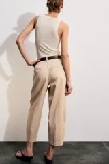 Pantalón tiro bajo color marrón, de corte globo y pernera recta con raya marcada al frente. Incluye trabillas y un cinturón marrón oscuro con hebilla metálica.