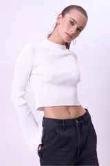 Blusa de punto acanalado color blanco, con cuello alto, corte cropped y mangas largas acampanadas.