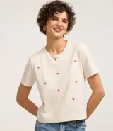 Remera de manga corta color crema con bordado de corazones rojos.