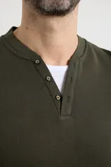 Remera de manga larga en tejido elastizado, color azul, con cuello tipo camisa, cartera con botones y detalles en eco gamuza en la base del cuello y la cartera.