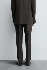 Pantalón de traje regular fit confeccionado en tejido de lana. Presenta bolsillos frontales, bolsillos traseros de vivo con botón y cierre frontal con cremallera y botón.