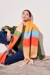 Bufanda larga tejida a rayas horizontales en tonos naranja, celeste, amarillo y beige, con flecos en los extremos.