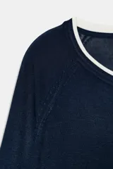 Jersey de punto efecto doble, color azul marino con detalles en blanco en el cuello, puños y ruedo. Presenta cuello redondo y manga larga con diseño de hombros raglán.