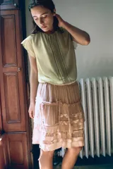 Falda corta de tiro bajo confeccionada en viscosa, con diseño de volantes superpuestos y frunces. Presenta detalle de lazadas laterales ajustables y cierre lateral con cremallera oculta.