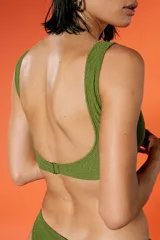 Top de bikini verde militar con textura arrugada, escote amplio y breteles fijos. Incluye bombacha vedetina con frente en V.