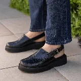 Sueco de cuero vacuno color marrón con estampado de cocodrilo, suela de goma negra y hebilla metálica plateada.