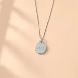 Conjunto de collar y dije de plata con cadena de eslabones y medalla redonda grabada con datos de nacimiento.