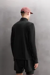 Sudadera técnica color vino tinto, de manga larga, con cuello subido y cierre frontal de cremallera. Presenta un bolsillo frontal con cierre de cremallera oculta en costura y detalle de logo estampado. El tejido tiene estructura waffle en el interior.