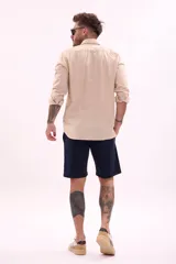 Camisa de manga larga color beige, con cuello clásico y botones frontales.