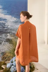 Vestido corto color beige de lino, con moldería amplia, manga corta, cuello mao y cierre frontal con botones dorados.