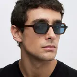 Lentes de sol con armazón marrón traslúcido de diseño cuadrado con bordes redondeados y lentes celestes.