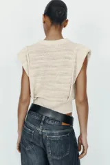 Jersey de punto sin mangas con cuello redondo, diseño de hombreras marcadas y textura acanalada horizontal.