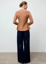 Chaqueta de punto entallada color tostado, con cuello en pico y cierre frontal de botones dorados efecto joya. Presenta mangas largas y un diseño estructurado.