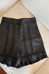 Short negro de cuero ovino con bordados y volados en el ruedo.