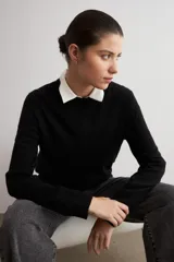Sweater clásico de punto color beige, de cuello redondo y manga larga con diseño ajustado.