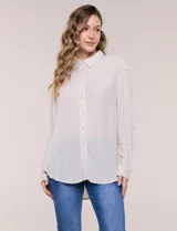 Camisa Magaschoni de silueta holgada y tejido texturizado color blanco, con cuello camisero, cierre frontal de botones, mangas largas con presilla para arremangar y diseño asimétrico con espalda más larga.
