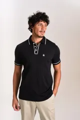 Polo de manga corta confeccionado en tejido interlock suave, color negro con detalles de vivos en color blanco en el cuello y las mangas. Presenta tapeta con botones y un bolsillo frontal con el logo bordado.