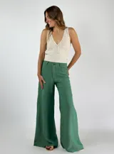 Pantalón de lino color verde, de corte palazzo, con cintura alta, bolsillos laterales y costuras decorativas en la parte delantera.