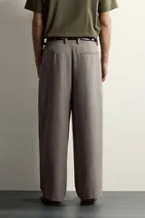 Pantalón relaxed fit de color blanco off-white, confeccionado en tejido con lino. Cuenta con pliegues frontales en la cintura, bolsillos delanteros y cierre frontal con cremallera y botón.
