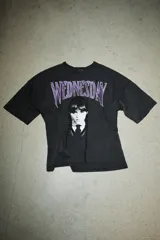 Camiseta de cuello redondo y manga corta con efecto lavado. Presenta una estampa frontal del personaje Wednesday con letras en color violeta.