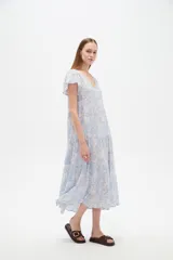 Vestido midi de viscosa con estampado floral en tonos celeste y blanco, cuello en V, mangas cortas y diseño holgado con volados escalonados en la falda.