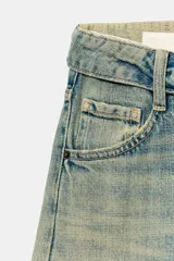 Jeans de tiro medio y corte ancho, confeccionados en denim con lavado estilo vintage de efecto desgastado. Presentan diseño de doble cinturilla superpuesta, cinco bolsillos tradicionales, trabillas para cinto y cierre frontal con cremallera y botón metálico.